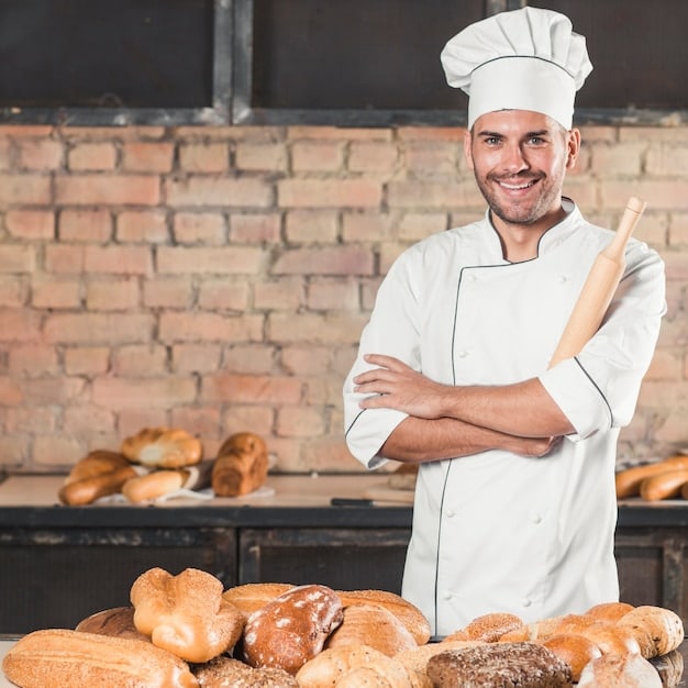 Smiling male baker with different type of baked breads in bakery
